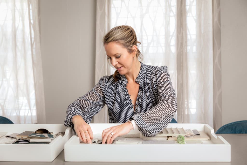 Designer curating teal, grey, and wood finish samples on a mood board.