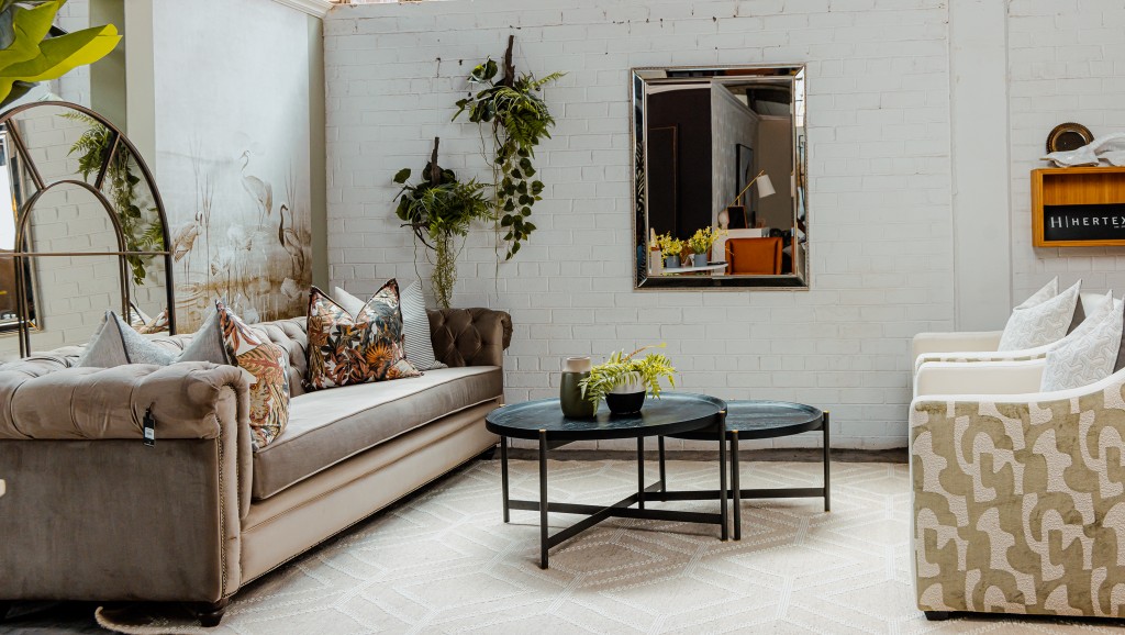 Showroom vignette with chesterfield sofa, nested tables, and patterned armchairs