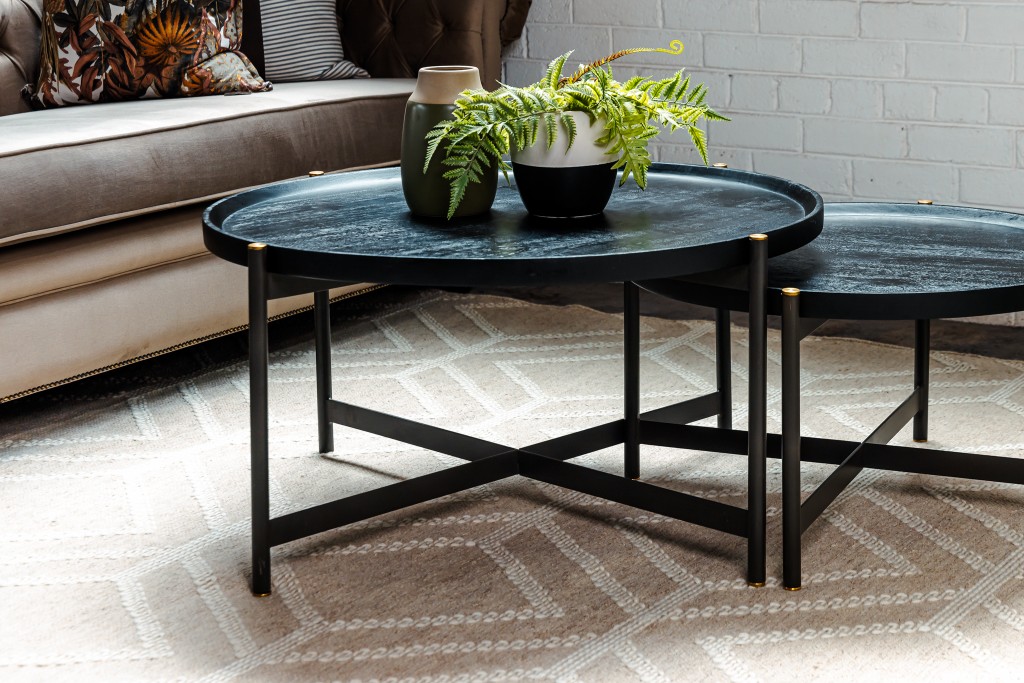 Nested black coffee tables with greenery on a patterned rug