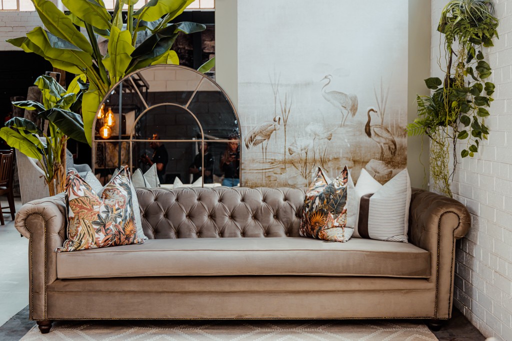 Chesterfield sofa with arched mirror and crane mural in a styled interior
